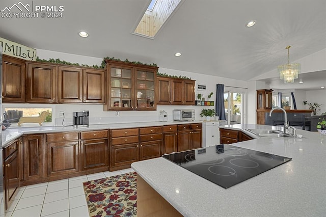 kitchen with lofted ceiling with skylight, sink, hanging light fixtures, light tile patterned floors, and black electric cooktop