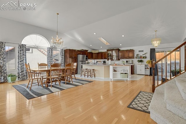 dining area featuring a chandelier, vaulted ceiling, and light wood-type flooring