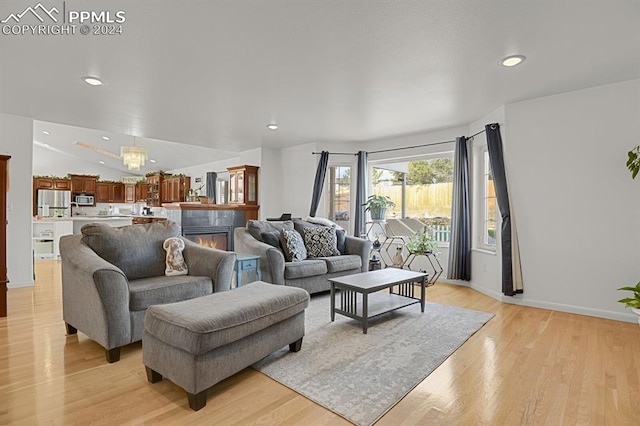 living room featuring light hardwood / wood-style flooring, a fireplace, and vaulted ceiling