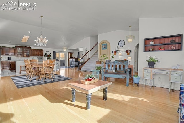 living room featuring a notable chandelier, light hardwood / wood-style flooring, and vaulted ceiling