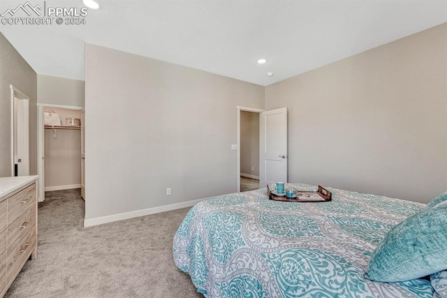 bedroom featuring a walk in closet, light carpet, and a closet