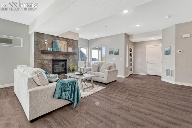 living room with a stone fireplace and dark hardwood / wood-style flooring