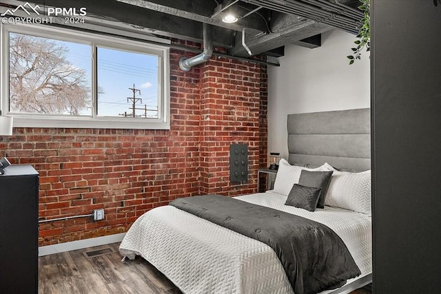 bedroom with wood-type flooring and brick wall