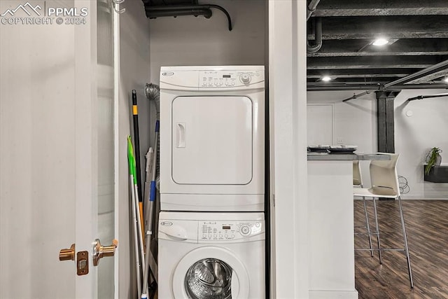 clothes washing area with dark hardwood / wood-style flooring and stacked washer and dryer