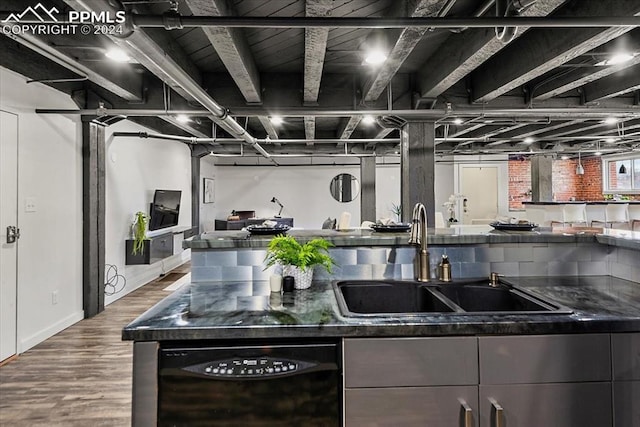 kitchen featuring dark stone countertops, sink, hardwood / wood-style floors, and black dishwasher