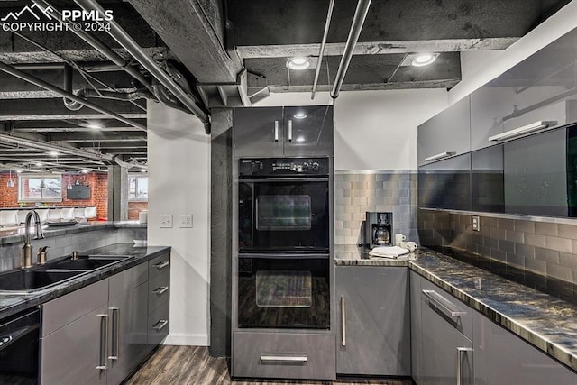 kitchen featuring backsplash, dark stone counters, black appliances, sink, and dark hardwood / wood-style floors