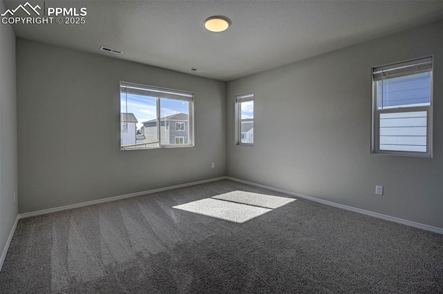 spare room with carpet, visible vents, and baseboards