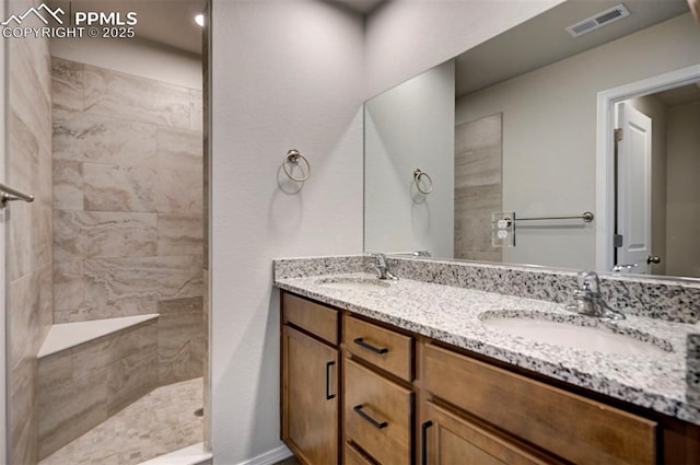 full bath with double vanity, walk in shower, a sink, and visible vents