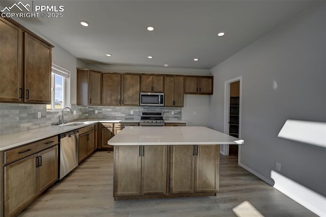 kitchen featuring a sink, a kitchen island, stainless steel appliances, and light countertops