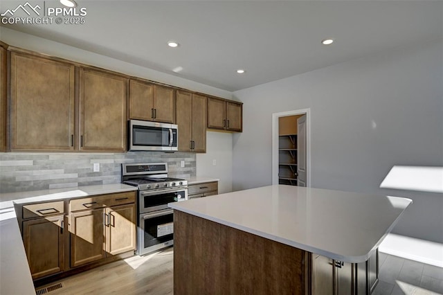 kitchen with tasteful backsplash, brown cabinetry, a center island, stainless steel appliances, and light countertops