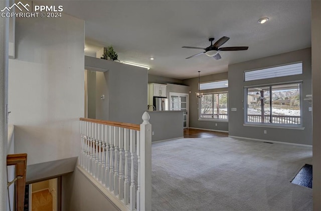 interior space featuring carpet and ceiling fan with notable chandelier