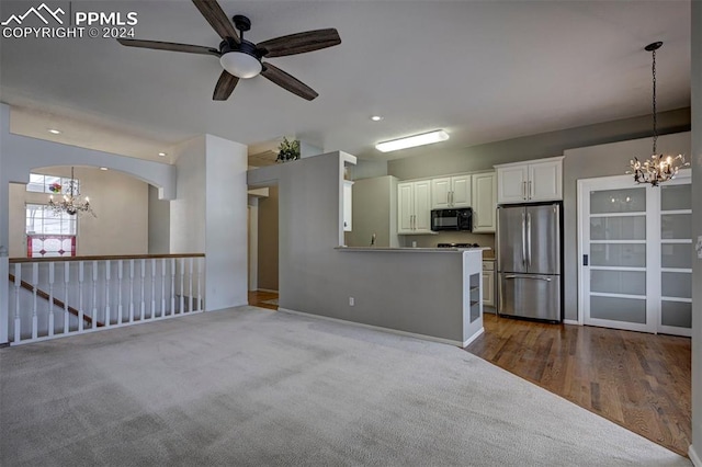 unfurnished living room with hardwood / wood-style floors and ceiling fan with notable chandelier