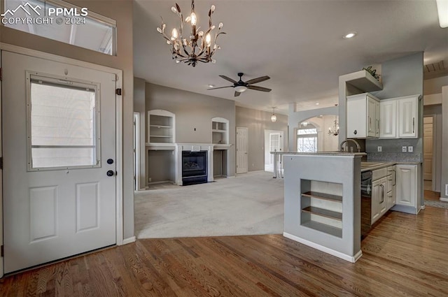 kitchen featuring light wood-type flooring, ceiling fan with notable chandelier, sink, decorative light fixtures, and white cabinetry