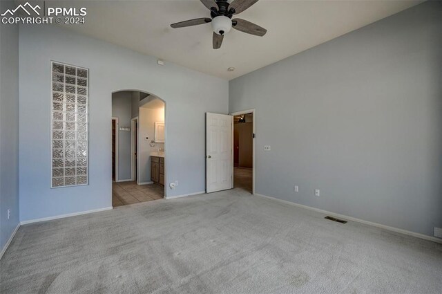 unfurnished bedroom with ensuite bathroom, ceiling fan, and light colored carpet