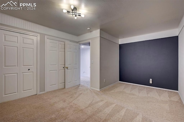 unfurnished bedroom with multiple closets, carpet, and a textured ceiling