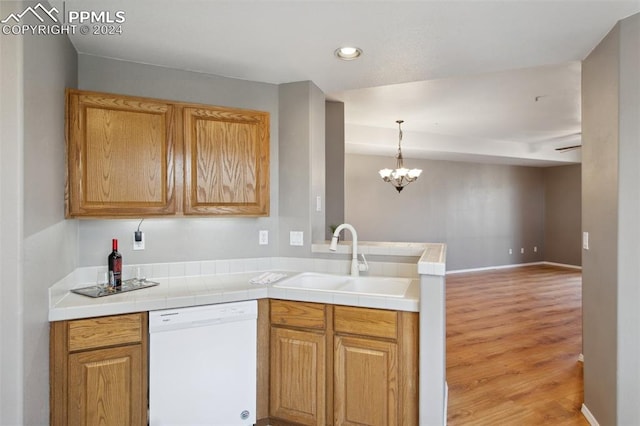 kitchen featuring kitchen peninsula, white dishwasher, sink, pendant lighting, and light hardwood / wood-style flooring