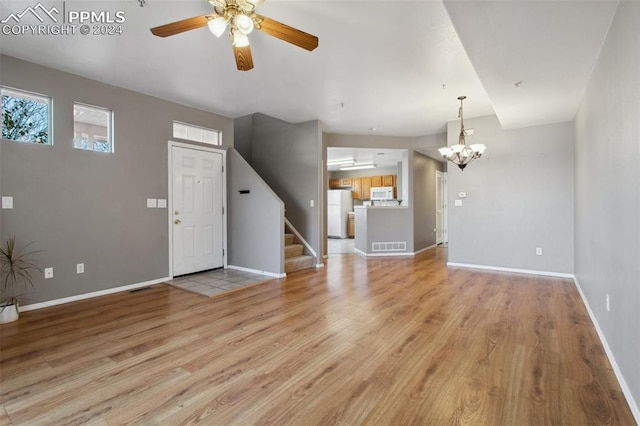 unfurnished living room with light hardwood / wood-style flooring and ceiling fan with notable chandelier