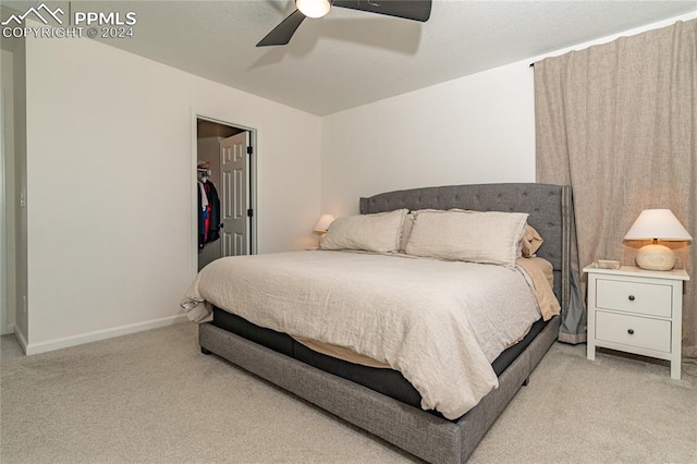 bedroom featuring light carpet, a walk in closet, a closet, and ceiling fan