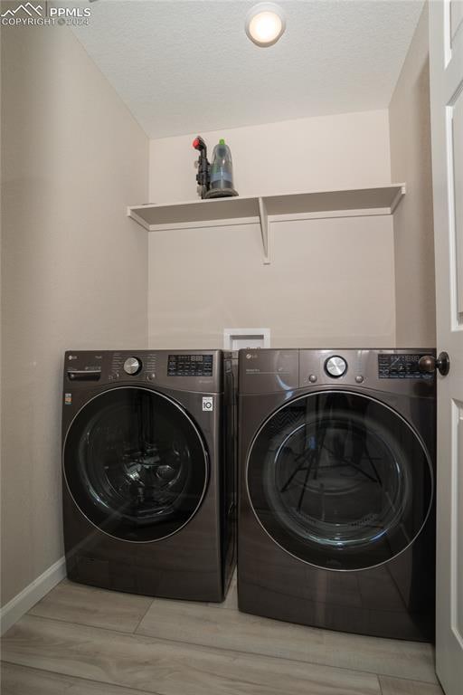 clothes washing area featuring washing machine and clothes dryer and light hardwood / wood-style flooring