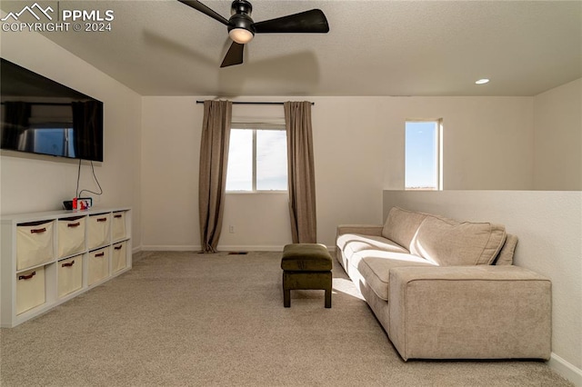 living area with ceiling fan and light colored carpet