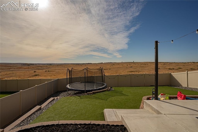 yard at dusk featuring a trampoline