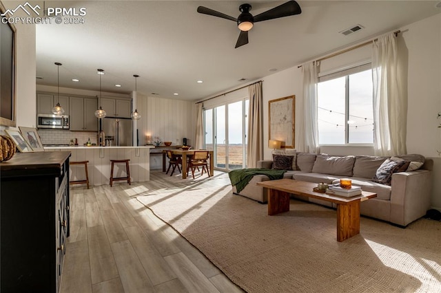 living room with light hardwood / wood-style flooring, plenty of natural light, and ceiling fan