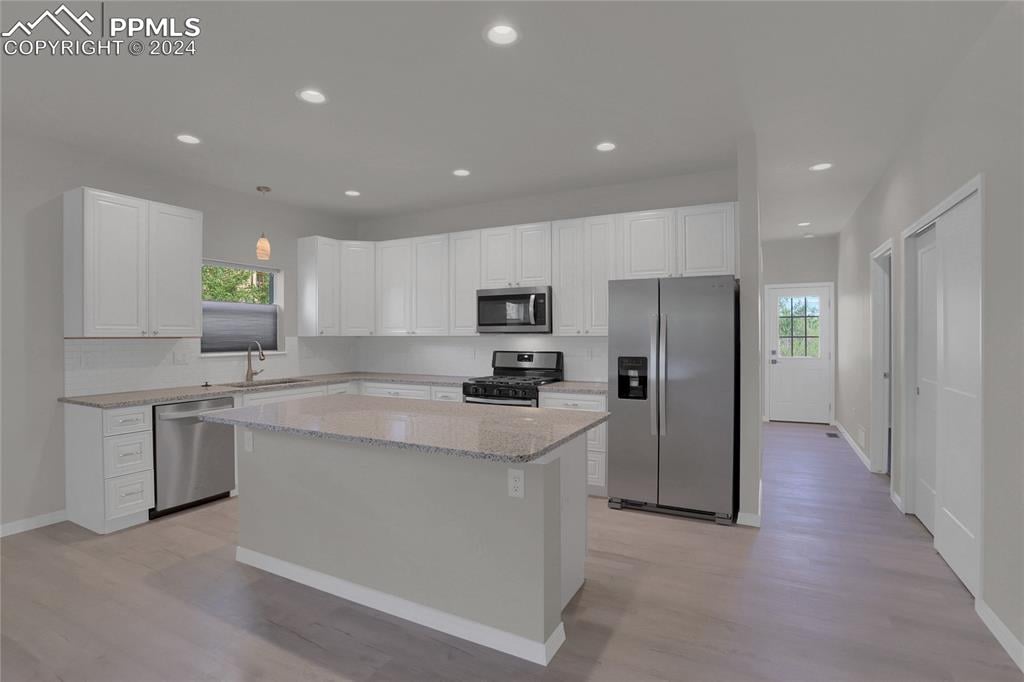 kitchen featuring stainless steel appliances, a kitchen island, a wealth of natural light, and sink