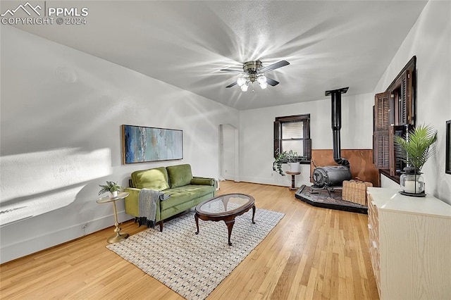 living room with a wood stove, ceiling fan, and hardwood / wood-style floors