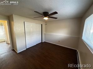 unfurnished bedroom featuring a textured ceiling, dark hardwood / wood-style flooring, a closet, and ceiling fan