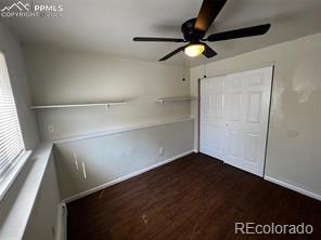 unfurnished bedroom featuring dark hardwood / wood-style flooring, ceiling fan, and a closet