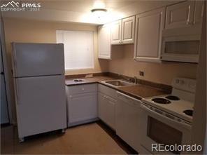 kitchen with white appliances, white cabinetry, and sink