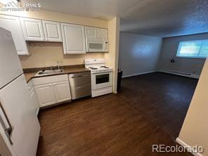 kitchen with white cabinets, dark hardwood / wood-style floors, white appliances, and sink