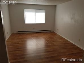 unfurnished room with dark hardwood / wood-style flooring and a baseboard radiator