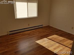 empty room featuring a baseboard radiator and dark hardwood / wood-style floors