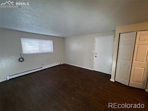 spare room featuring baseboard heating and dark wood-type flooring