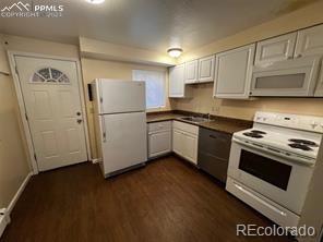 kitchen with white cabinets, dark hardwood / wood-style floors, white appliances, and sink