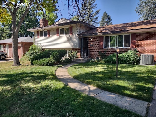 tri-level home featuring a front yard and cooling unit