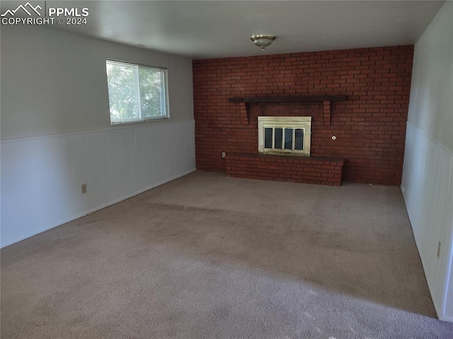 unfurnished living room featuring carpet floors, brick wall, and a brick fireplace