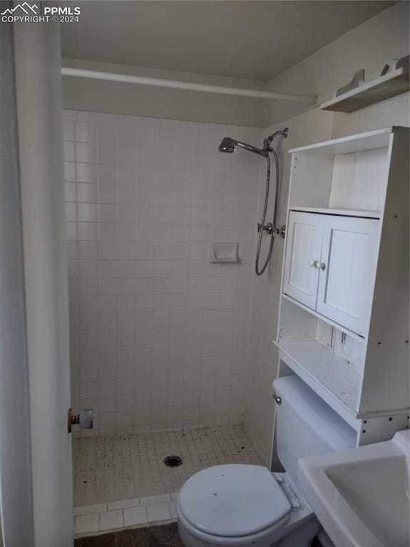 bathroom featuring tiled shower, sink, tile patterned flooring, and toilet