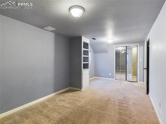 unfurnished room featuring a textured ceiling and light colored carpet