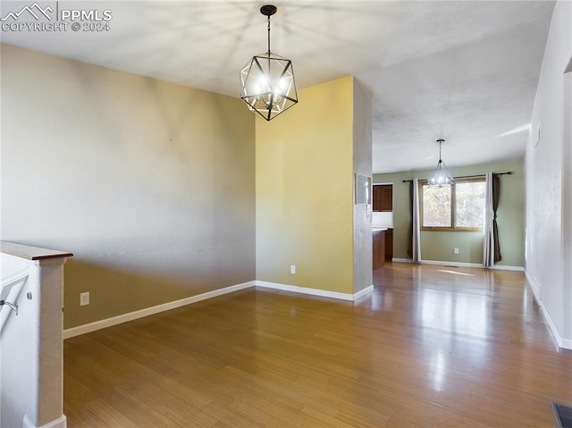 unfurnished dining area with hardwood / wood-style flooring and a chandelier