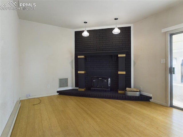 unfurnished living room featuring hardwood / wood-style flooring and a brick fireplace