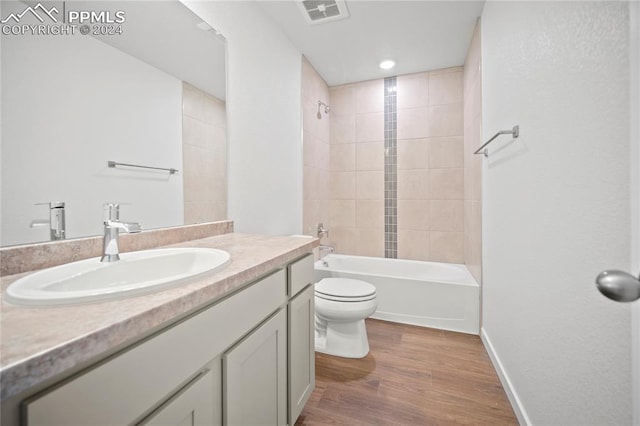 full bathroom with hardwood / wood-style floors, vanity, toilet, and tiled shower / bath