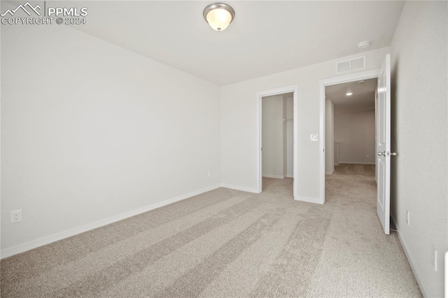 unfurnished bedroom with light carpet, a spacious closet, and a closet