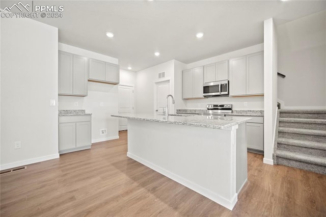 kitchen featuring sink, an island with sink, stainless steel appliances, and light hardwood / wood-style flooring