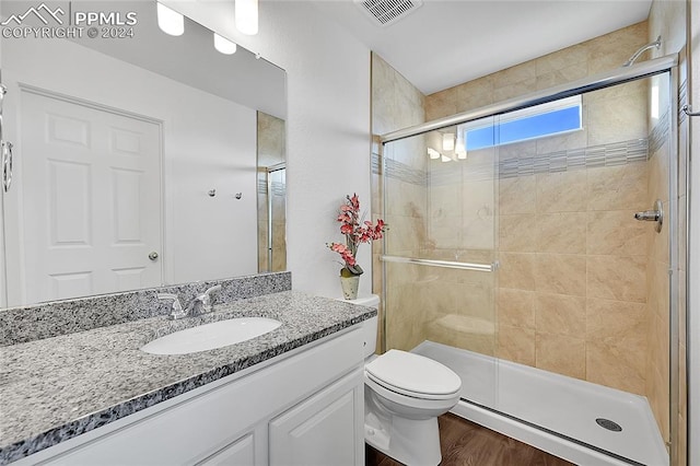 bathroom featuring vanity, hardwood / wood-style flooring, toilet, and a shower with door