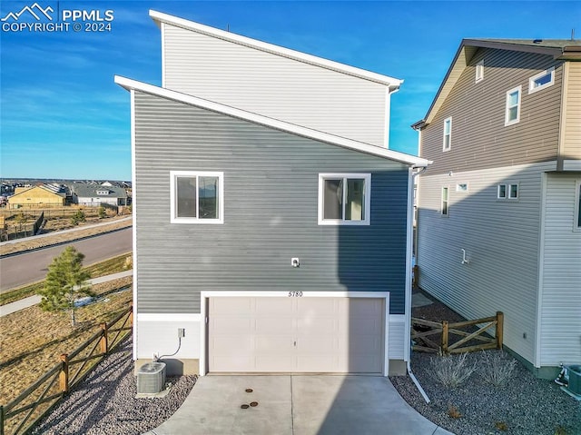 back of house with a garage and central air condition unit