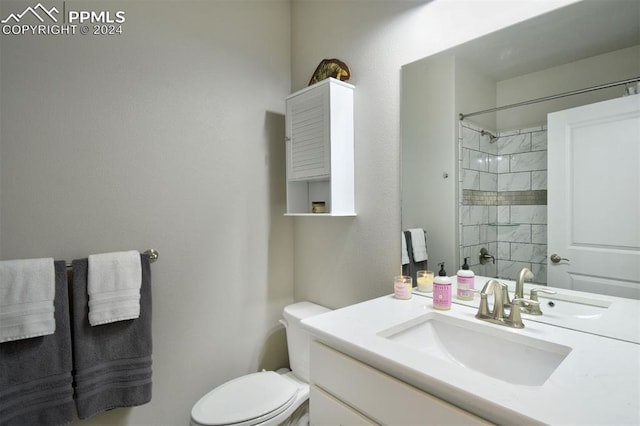 bathroom with tiled shower, vanity, and toilet