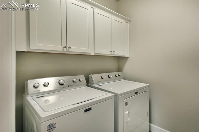 washroom featuring washing machine and clothes dryer and cabinets