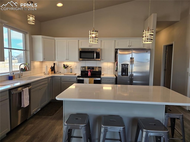 kitchen with pendant lighting, a center island, lofted ceiling, sink, and appliances with stainless steel finishes